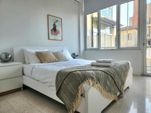 a bedroom with a white bed with a blanket on it at Sunny Eclectic 3BR house in Gemmayze in Beirut