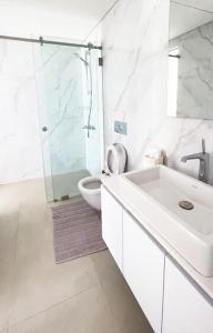 a white bathroom with a sink and a toilet at Amchit Bay Beach Residences 2BR w Private Pool in Jbeil