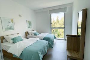 2 camas en una habitación blanca con ventana en Amchit Bay Beach Residences 3BR w Indoor Jacuzzi en Jbeil