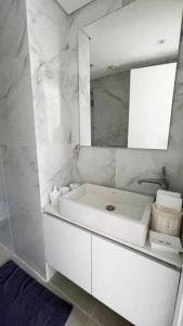 Baño blanco con lavabo y espejo en Amchit Bay Beach Residences 3BR w Indoor Jacuzzi en Jbeil