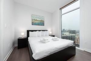 een slaapkamer met een groot wit bed en een groot raam bij Toronto Condo with a View, St. Lawrence Market in Toronto