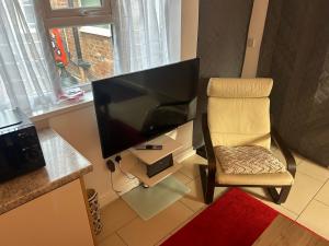 a desk with a chair and a large screen television at Airport Retreat in Handforth