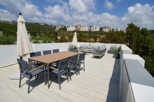 a patio with a wooden table and chairs and an umbrella at Amchit Bay Beach Residences 3BR Rooftop w Jacuzzi in Jbeil
