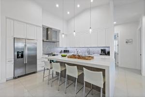 a white kitchen with a large island with bar stools at Pet-friendly home near shops with pool and spa in Marco Island