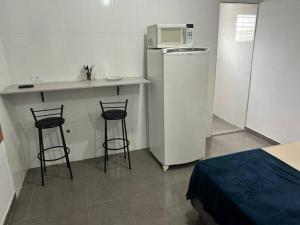 a small kitchen with two bar stools and a microwave at Studio Zona norte SP - proximo Expo Center Norte Vila Guilherme in São Paulo
