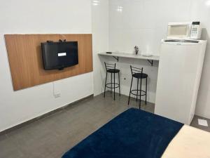 a room with a tv and a counter with stools at Studio Zona norte SP - proximo Expo Center Norte Vila Guilherme in Sao Paulo