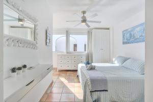 a white bedroom with a bed and a ceiling fan at SunsetView apartment El Cotillo 2-4 personas in Cotillo