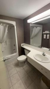 a bathroom with a toilet and a sink and a mirror at Comfort Inn Lundy's Lane in Niagara Falls