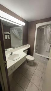 a bathroom with a sink and a toilet and a mirror at Comfort Inn Lundy's Lane in Niagara Falls
