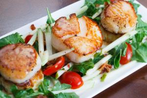 a plate of food with scallops and a salad at The White Buffalo Club in Jackson