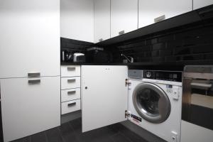 a white kitchen with a washing machine in it at Chic Flat in Oxford Circus in London