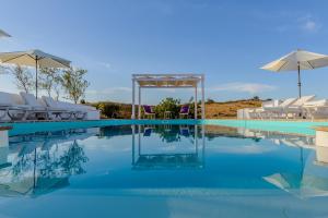a swimming pool with white chairs and an umbrella at Monte Do Malhao - Art, Eco & Spa in Castro Marim