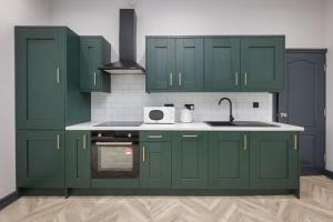 a kitchen with green cabinets and a sink at Ettie and Gigi's in Blackpool