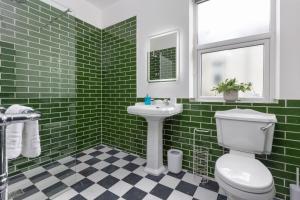 een groene betegelde badkamer met een toilet en een wastafel bij Ettie and Gigi's in Blackpool