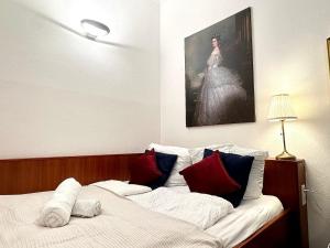 una cama con almohadas rojas y azules y una pintura en Central - 30 m² - Next to Augarten, en Viena