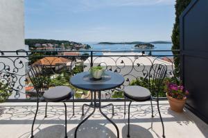 una mesa y sillas en un balcón con vistas en Villa Milton Luxe Rooms, en Hvar