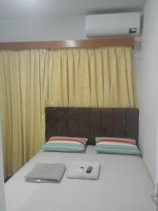 a bed with two pillows and a laptop on it at AP Novo, Cama Queen Size Nova no Centro de Blu in Blumenau