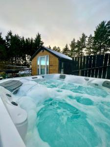 una bañera de hidromasaje cubierta de nieve frente a una casa en Speir dorcha cabin, en Omagh