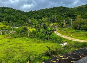 un camino junto a una exuberante colina verde con árboles en Chacara com churrasqueira em Saquarema RJ, en Jaconé