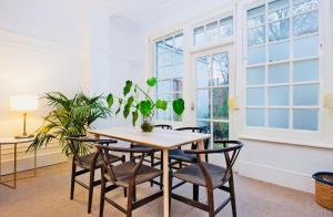 a dining room with a table and chairs and windows at Spacious & Charming garden flat -Zone 2- Great for Central London access in London