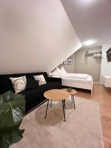 NAMI - ROBIN - Helle Apartments mitten in der Stadt في ميمينجين: غرفة معيشة مع أريكة سوداء وطاولة