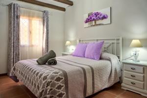 a bedroom with a bed with purple pillows and a window at Casa Rural Vistaluque in Luque