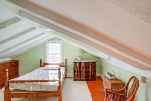 Schlafzimmer im Dachgeschoss mit einem Bett und einem Stuhl in der Unterkunft Cozy Berkshires Cottage with 11 Private Acres! in Lee