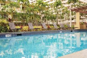 uma piscina num hotel com cadeiras e palmeiras em Brooks Beach Vacations Wyndham 4 Star Resort 1805 Waikiki em Honolulu