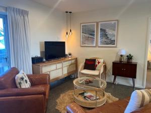a living room with a couch and a tv at Longitude Apartments Raglan in Raglan