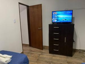 a bedroom with a television on a dresser with a bed at Rioja Suites - Departamento Céntrico. in La Rioja
