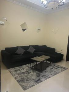 sala de estar con sofá negro y mesa en One bedroom apartment in Jimi en Al Ain