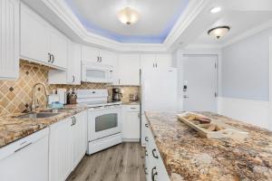 a kitchen with white cabinets and a marble counter top at Welcome to Beach Villa's # 405 Vacation Rental - 250 Estero Blvd condo in Fort Myers Beach