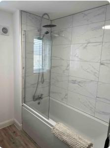 a bathroom with a shower with white marble walls at Cobbeydale room in Silsden