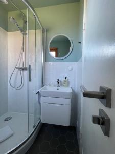 a white bathroom with a shower and a sink at Captain's Lounge - Bungalow XL in Westerland (Sylt)