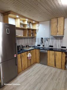 eine Küche mit einem Kühlschrank aus Edelstahl und Holzschränken in der Unterkunft Котеджі Цімбори in Jablunyzja