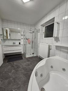 bagno bianco con vasca e doccia di Haus an der Weser Ferienwohnung a Brevörde