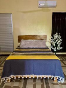 uma cama com um cobertor azul e amarelo em Casa Guiba 2 Puerto Escondido em Puerto Escondido