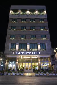 un edificio de apartamentos por la noche con bancos delante en Asenappar Hotel, en Erbil