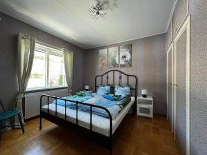 a bedroom with a bed with blue sheets and a window at Ferienhaus am Wald im Land der Elche in Torsby