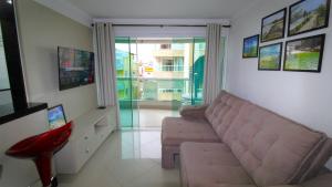 sala de estar con sofá y taburete rojo en 1020 - Apto 03 dormitórios para locação em Bombinhas - Residencial Alameda Verde Apto 201, en Bombinhas