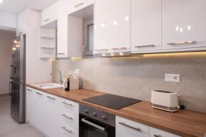 cocina con armarios blancos y encimera en Semi Basement Apartment by Sunshine Place World, en Playa Kalo Livadi