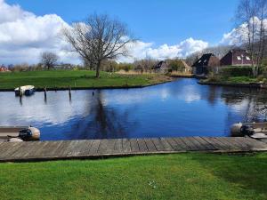rzeka z drewnianą ścieżką i domy w tle w obiekcie Amazing holiday home in Friesland with Sauna and outdoor Spa w mieście Earnewâld