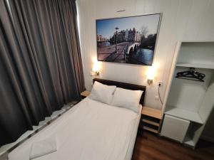 a small bedroom with a bed and a picture on the wall at Hotel Holland Lodge in Utrecht
