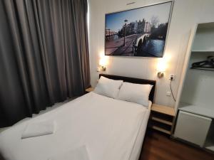 a bedroom with a white bed with a picture on the wall at Hotel Holland Lodge in Utrecht