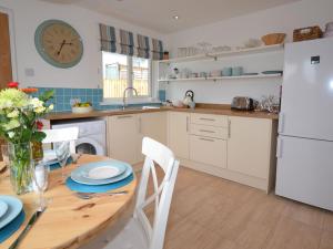 a kitchen with a wooden table and a white refrigerator at 2 Bed in Bude AGLET in Bude