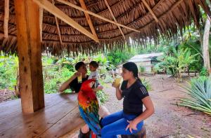 Kobieta z papugą siedzącą obok kobiety w obiekcie ARAPARI AMAZON LODGE w mieście Mazán