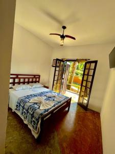 a bedroom with a bed and a ceiling fan at Pousada Aquarela Maresias in Maresias