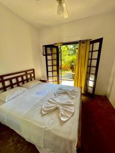 a bedroom with a large bed with a bow on it at Pousada Aquarela Maresias in Maresias