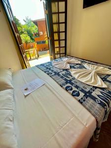 a bed with a card on top of it at Pousada Aquarela Maresias in Maresias