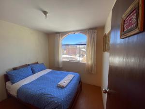 a bedroom with a bed with a blue comforter and a window at Homestay Pachamama in Cabanaconde